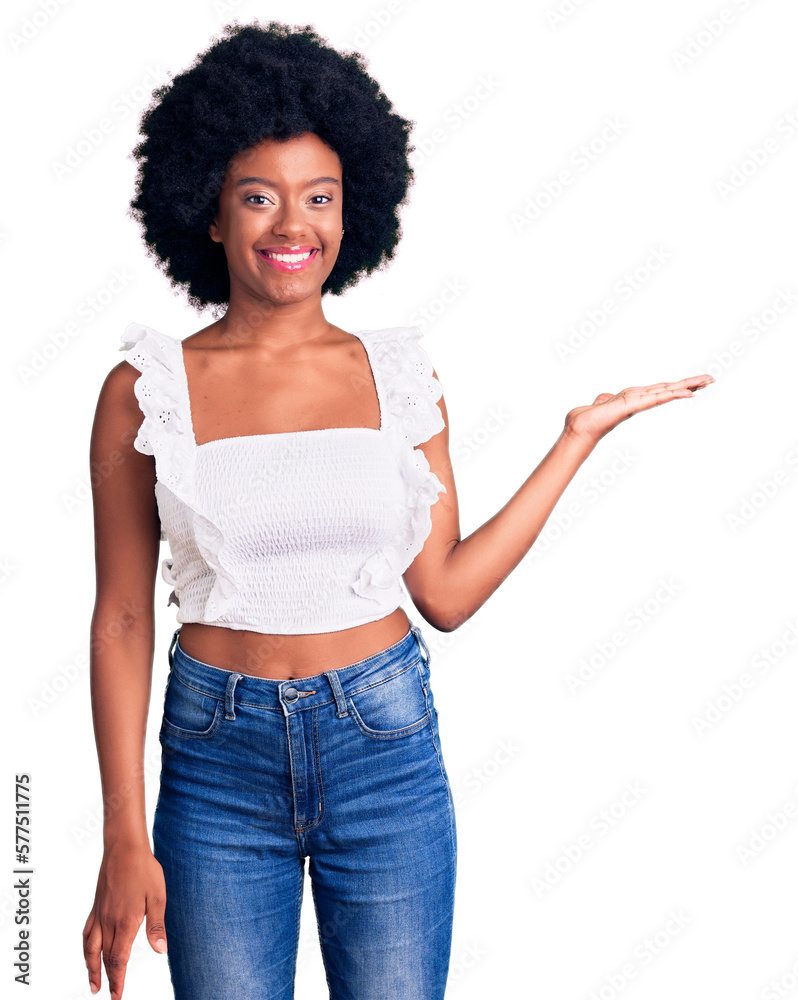 Young african american woman wearing casual clothes smiling cheerful presenting and pointing with palm of hand looking at the camera. Young african american woman wearing casual clothes smiling cheerful presenting and pointing with palm of hand looking at the camera.