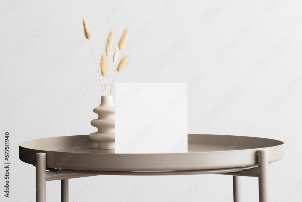 Square invitation card mockup with a lagurus decoration on the beige table.