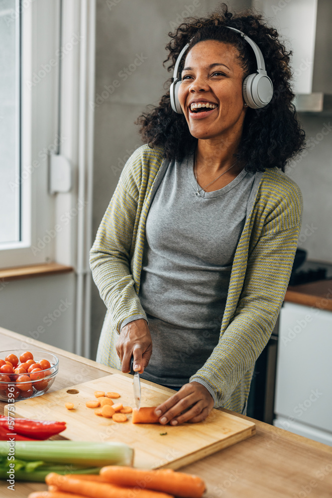 A happy woman is listening to music while cooking