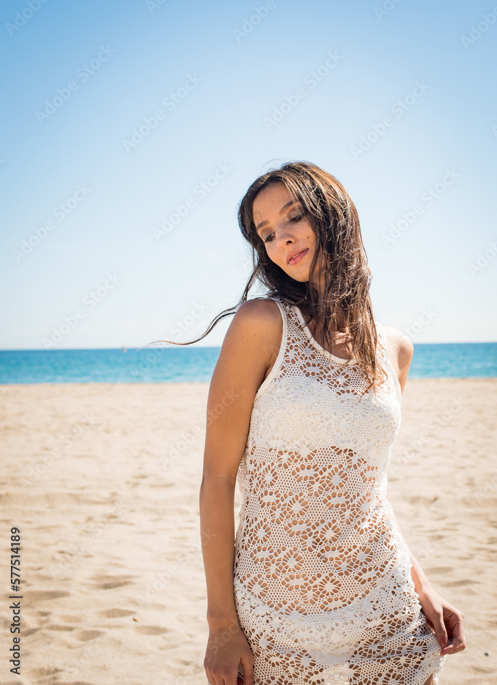 Donna con vestito bianco cammina sulla spiaggia