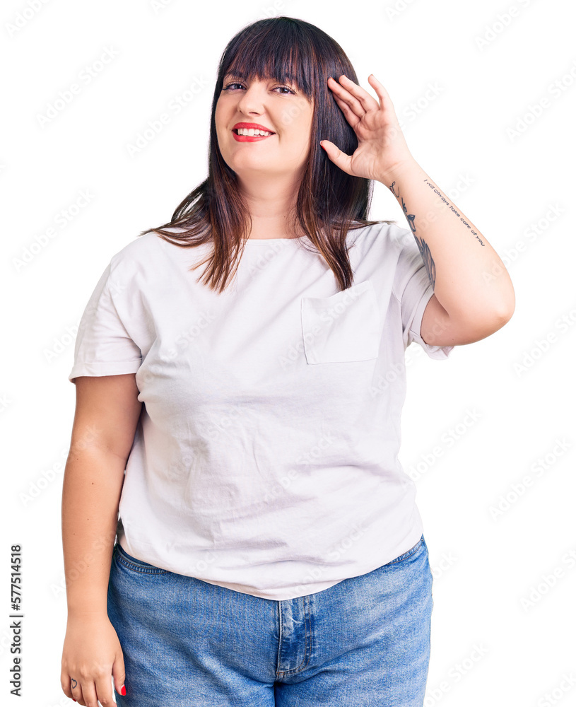 Young plus size woman wearing casual clothes smiling with hand over ear listening an hearing to rumor or gossip. deafness concept. Young plus size woman wearing casual clothes smiling with hand over ear listening an hearing to rumor or gossip. deafness concept.