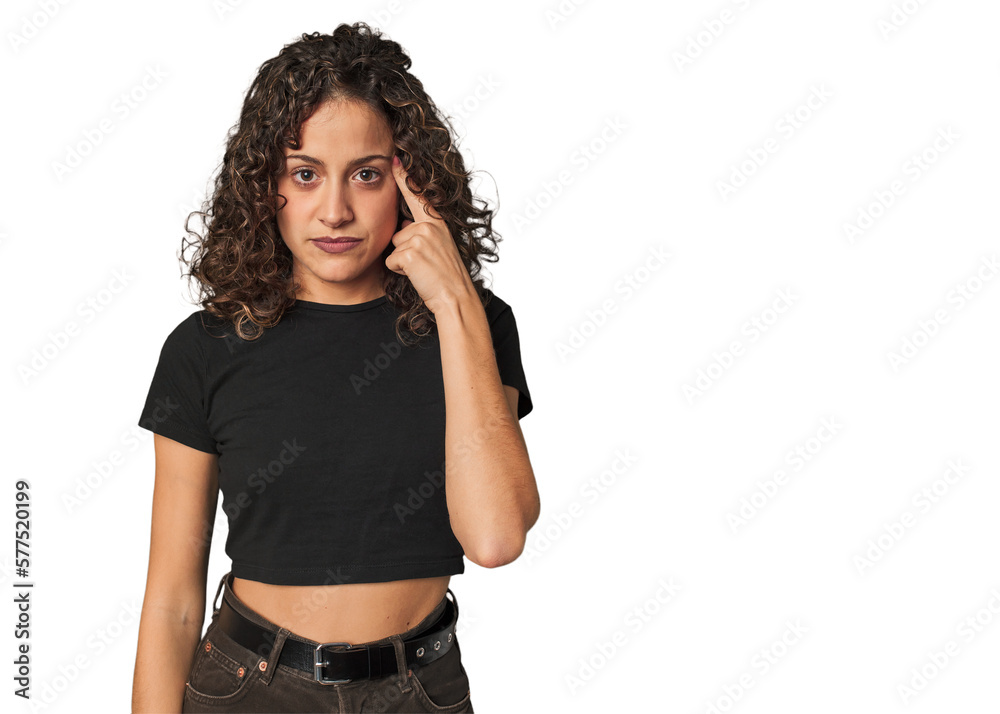Radiant young woman with stunning curls pointing temple with finger, thinking, focused on a task. Radiant young woman with stunning curls pointing temple with finger, thinking, focused on a task.