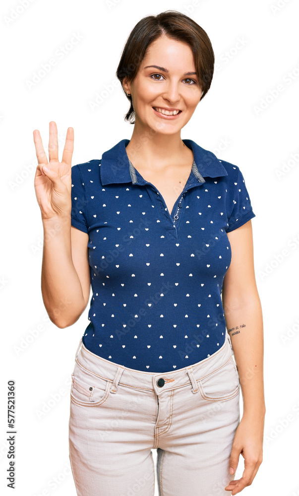 Young brunette woman with short hair wearing casual clothes showing and pointing up with fingers number three while smiling confident and happy.