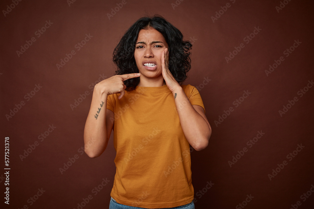 Young colombian curly hair woman isolated on brown background having a strong teeth pain, molar ache. Young colombian curly hair woman isolated on brown background having a strong teeth pain, molar ache.