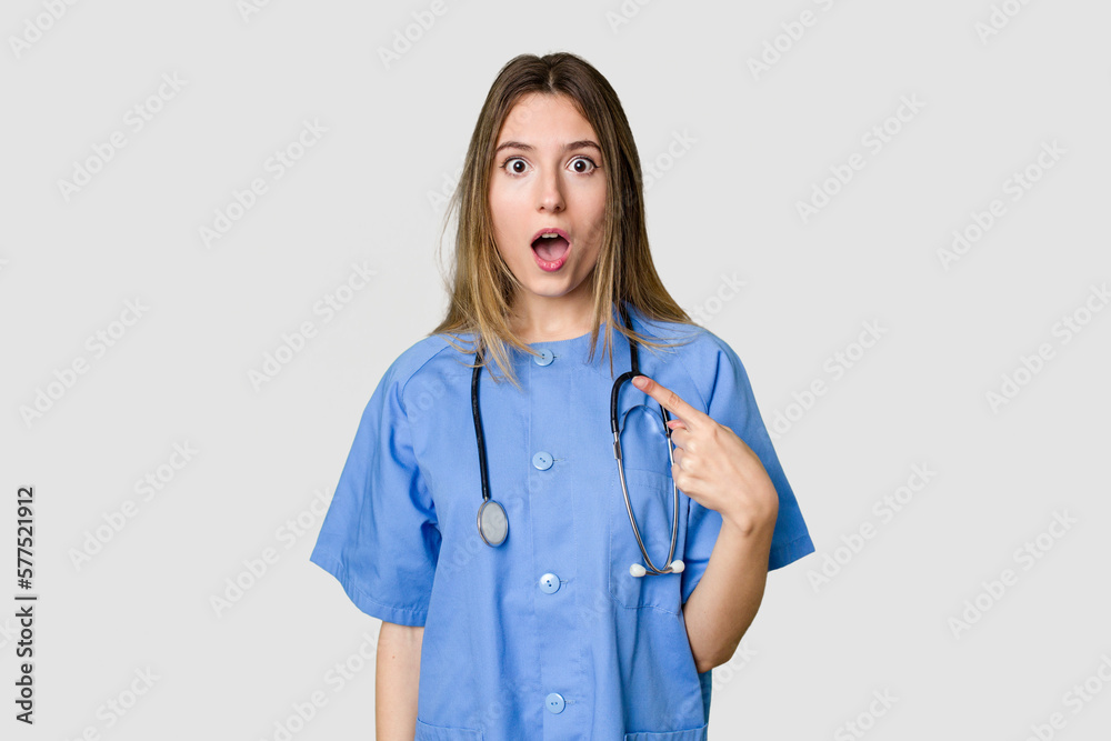 Young female nurse in uniform with stethoscope, symbol of care and dedication to patients pointing to the side Young female nurse in uniform with stethoscope, symbol of care and dedication to patients pointing to the side