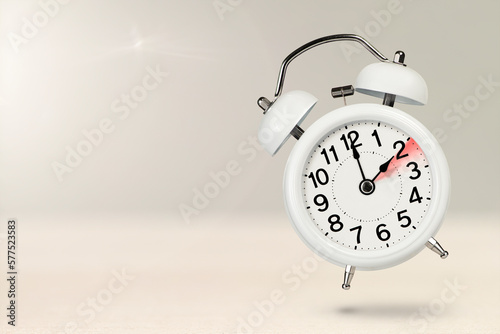 Change time. Winter time concept, on a wooden background. A white alarm clock with a minute hand indicates that the time has been changed to an hour ago with copy space.