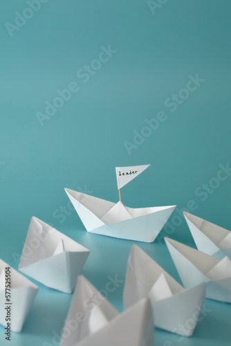 Leadership, teamwork and courage concept. White paper boats on blue background.