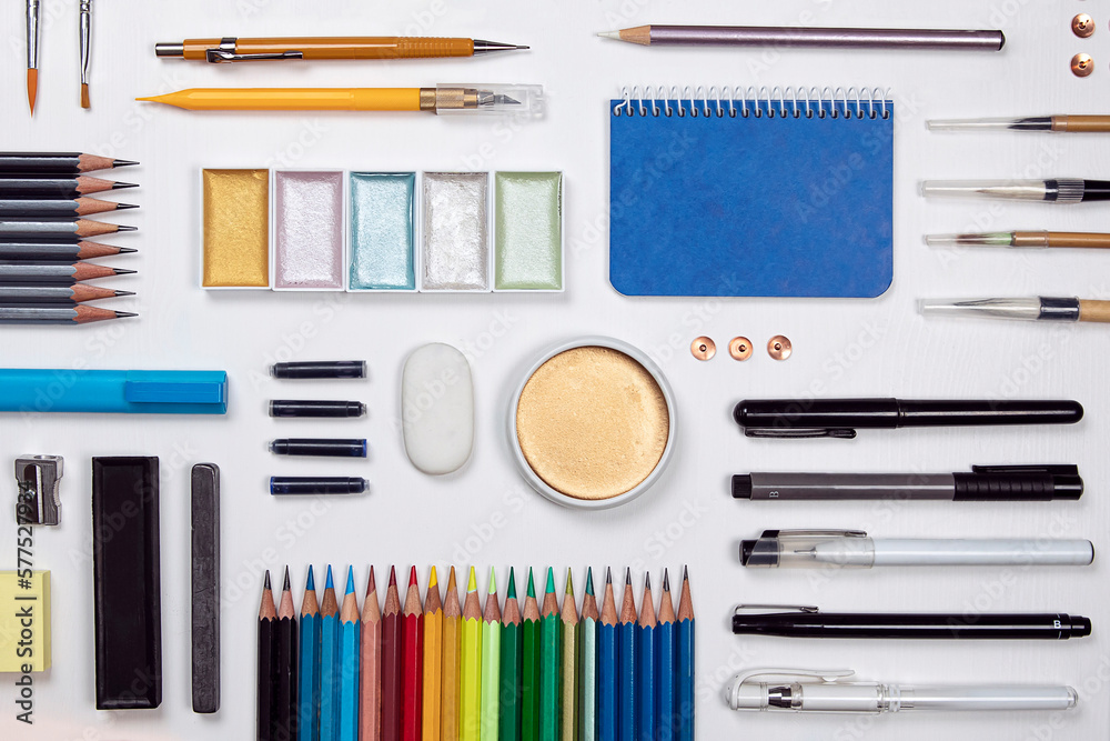 Stationery flat lay composition on white background. Creative designer, artist, equipment on white desk. Variety of office objects as paint, brush, pencil, marker pen and more view from above.