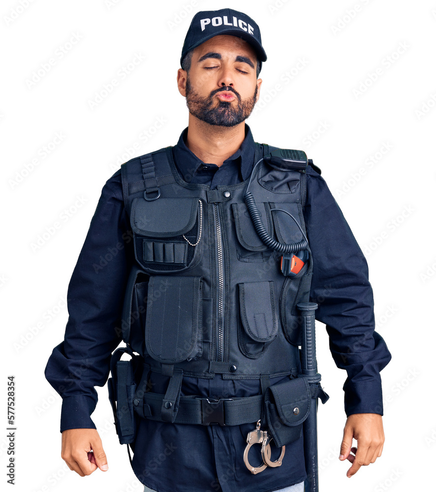 Young hispanic man wearing police uniform looking at the camera blowing a kiss on air being lovely and sexy. love expression. Young hispanic man wearing police uniform looking at the camera blowing a kiss on air being lovely and sexy. love expression.