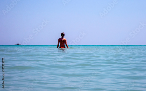 Giovane donna in bikini in piedi nell'acqua del mare e con lo sguardo rivolto all'orizzonte. photo