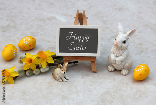 Happy Easter written on an easel with Easter decorations in yellow and white.