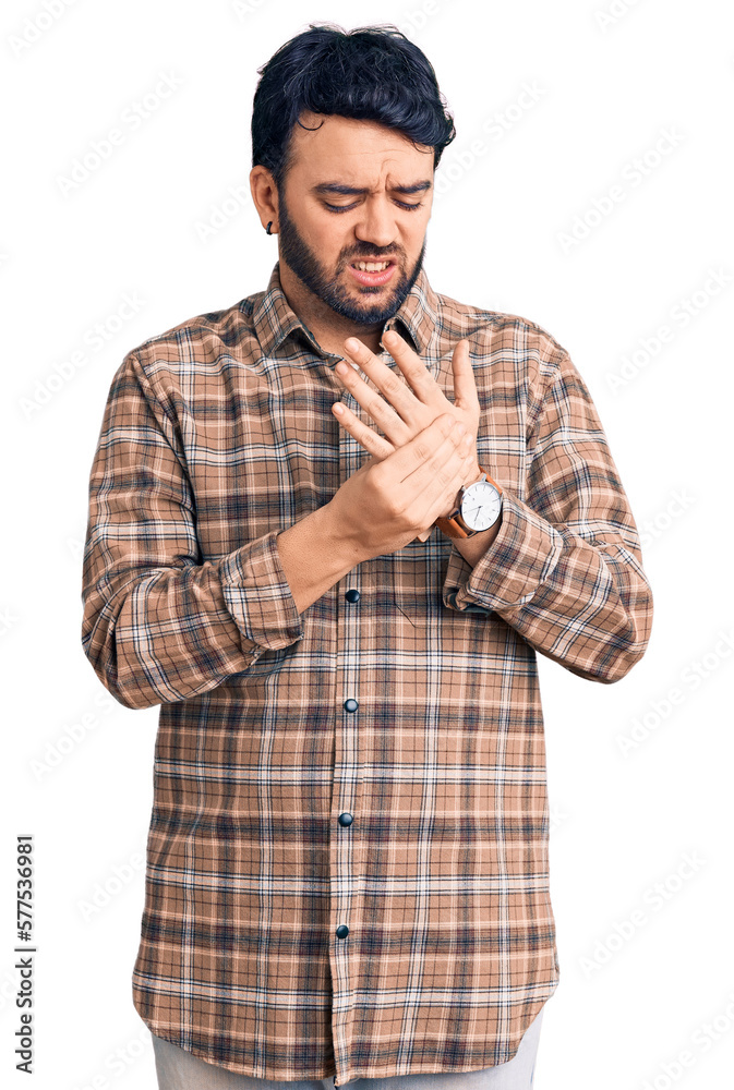 Young hispanic man wearing casual clothes suffering pain on hands and fingers, arthritis inflammation Young hispanic man wearing casual clothes suffering pain on hands and fingers, arthritis inflammation