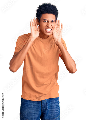 Young african american man wearing casual clothes trying to hear both hands on ear gesture, curious for gossip. hearing problem, deaf