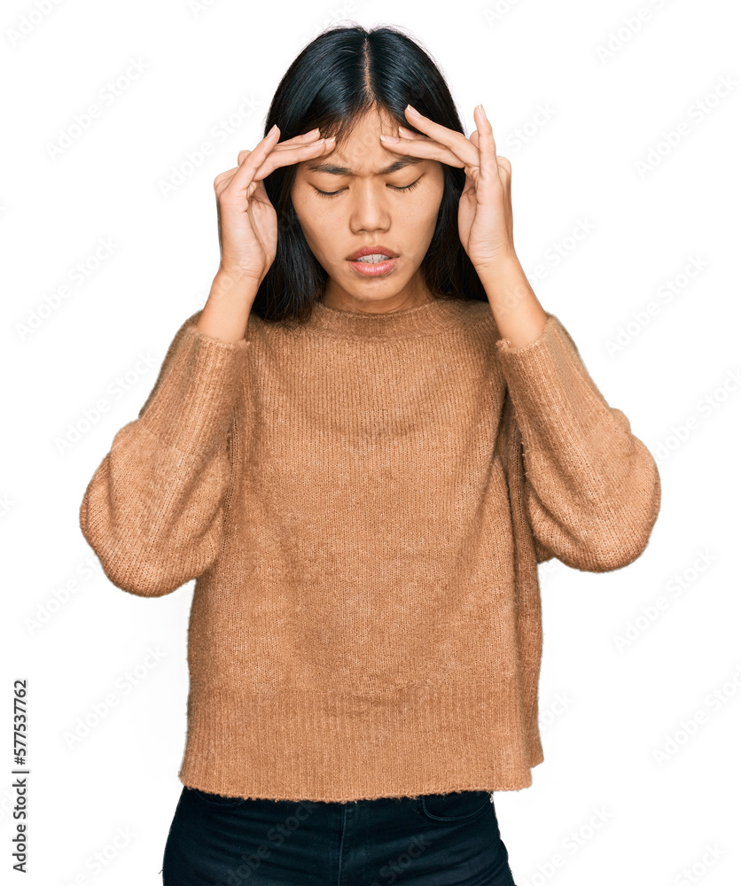 Beautiful young asian woman wearing casual winter sweater with hand on head for pain in head because stress. suffering migraine. Beautiful young asian woman wearing casual winter sweater with hand on head for pain in head because stress. suffering migraine.