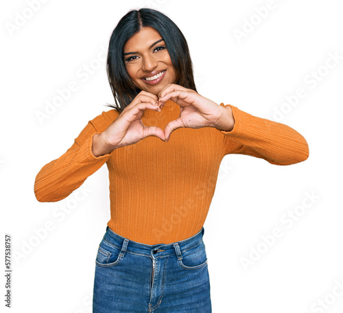 Young latin transsexual transgender woman wearing casual clothes smiling in love doing heart symbol shape with hands. romantic concept.