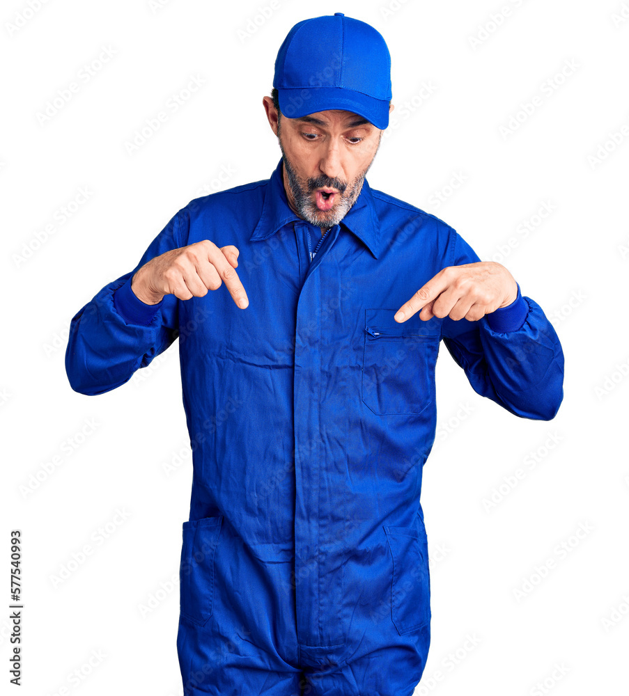 Middle age handsome man wearing mechanic uniform pointing down with fingers showing advertisement, surprised face and open mouth Middle age handsome man wearing mechanic uniform pointing down with fingers showing advertisement, surprised face and open mouth