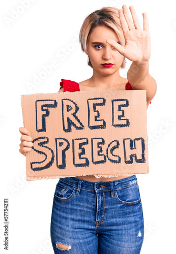 Young beautiful blonde woman holding free speech banner with open hand doing stop sign with serious and confident expression, defense gesture © Krakenimages.com