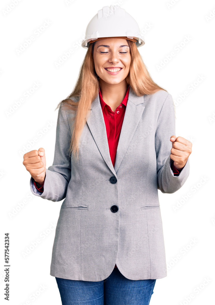 Beautiful young woman wearing architect hardhat very happy and excited doing winner gesture with arms raised, smiling and screaming for success. celebration concept.