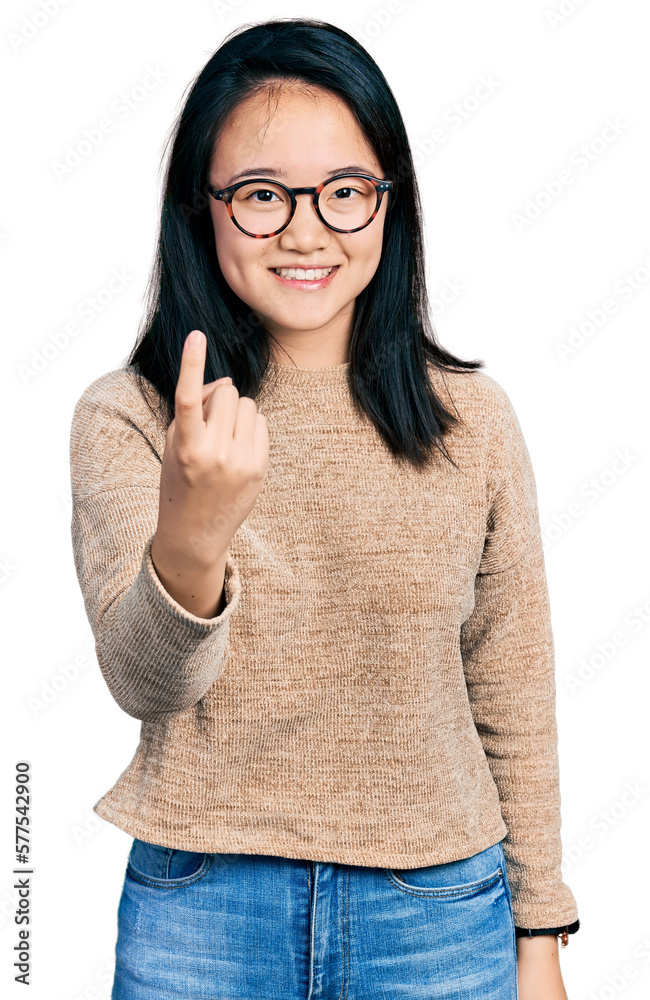 Young chinese woman wearing casual sweater and glasses beckoning come here gesture with hand inviting welcoming happy and smiling Young chinese woman wearing casual sweater and glasses beckoning come here gesture with hand inviting welcoming happy and smiling
