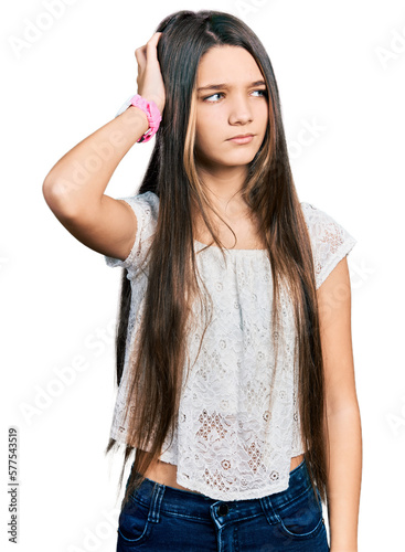Young brunette girl with long hair wearing white shirt confuse and wondering about question. uncertain with doubt, thinking with hand on head. pensive concept. © Krakenimages.com