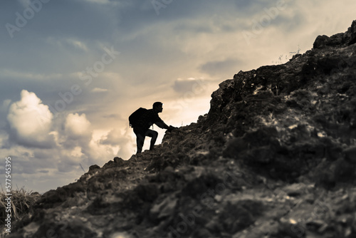 Hiker climbing up mountain edge. 