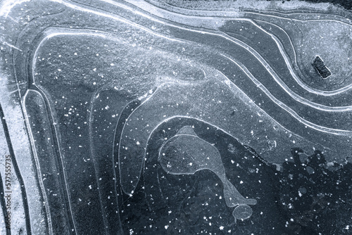 Textured ice background with white snow curves on the surface, and an air bulb in the shape of a whale. The photo showcases the beauty and intricacy of nature's designs in a winter landscape.