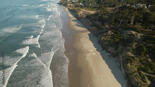 Drone flying over the beach and blue-turquoise water on a beautiful sunny day in Oregon
