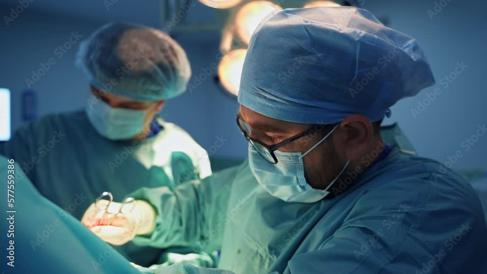 Male Caucasian doctor uses diverse tools at work changing them fast. Side view portrait of a hardworking healthcare professional at operation. Male Caucasian doctor uses diverse tools at work changing them fast. Side view portrait of a hardworking healthcare professional at operation.
