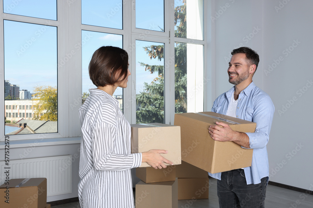 Happy couple with moving boxes near big window in new apartment Happy couple with moving boxes near big window in new apartment