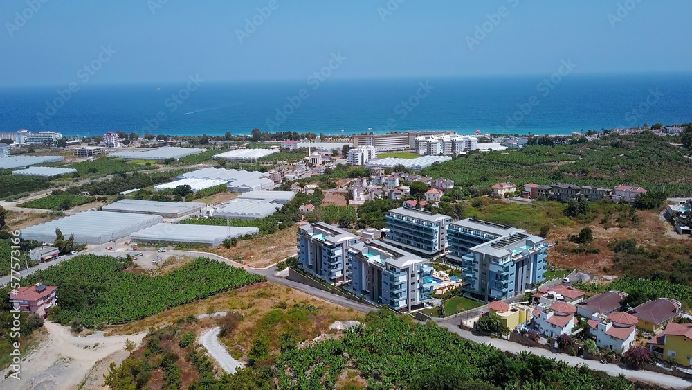 View from a drone flight to the resort area. Clip. View of the sea and the area of hotels and houses with green fields