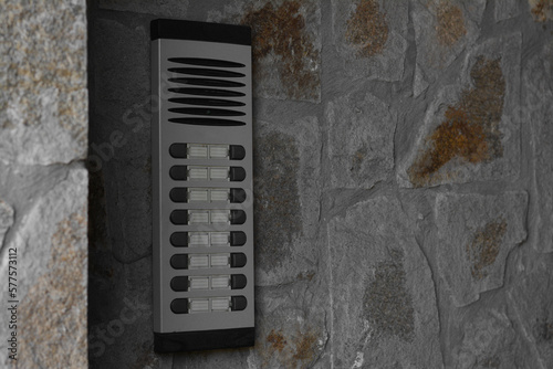 Modern intercom on concrete wall with stone fragments, space for text. Security system
