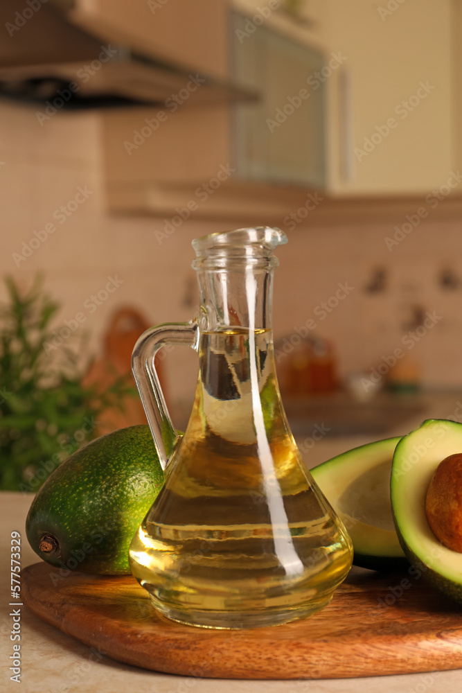 Fresh avocados and jug of cooking oil on beige marble table in kitchen Fresh avocados and jug of cooking oil on beige marble table in kitchen