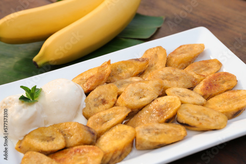 Tasty deep fried banana slices with ice cream and mint on wooden table, closeup