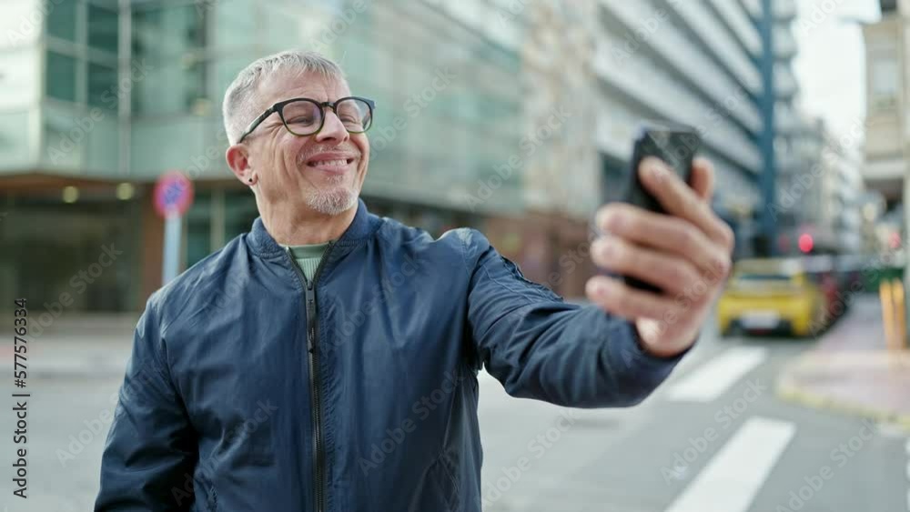 Middle age grey-haired man smiling confident having video call at street Middle age grey-haired man smiling confident having video call at street