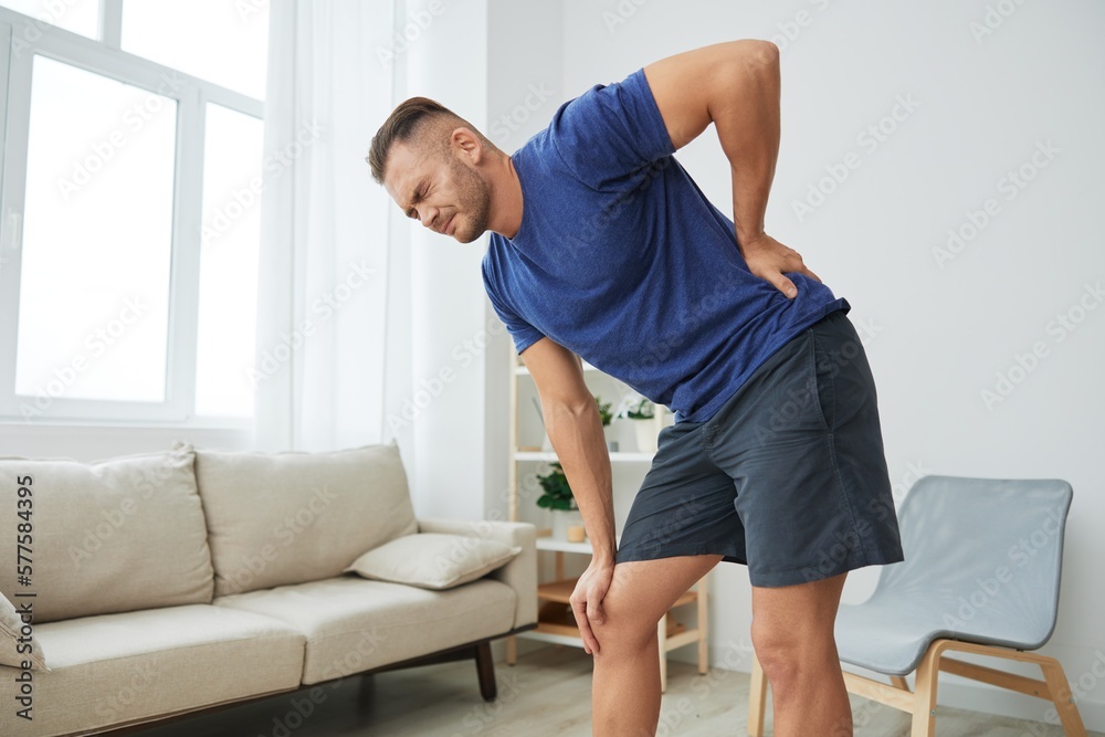 Man backache neck and shoulder pain, inflammation of muscles and ligaments rupture during sports, inflammation and injury, in a blue t-shirt at home