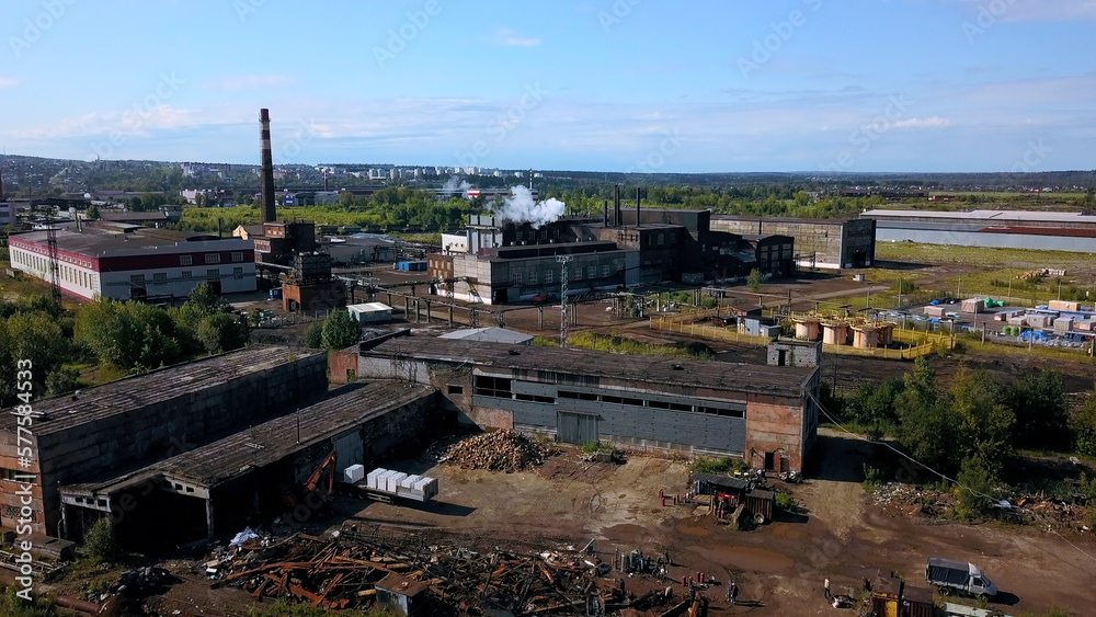 Urban industry from drone. Action. A view from a height to the outskirts with tall chimneys from where smoke comes out.