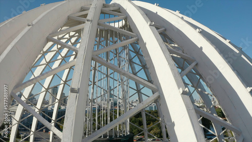 Top view of domed structure with beams. Stock footage. Beautiful architecture of metal dome with beams. Dome made of metal semi-arches with air space on background of modern city