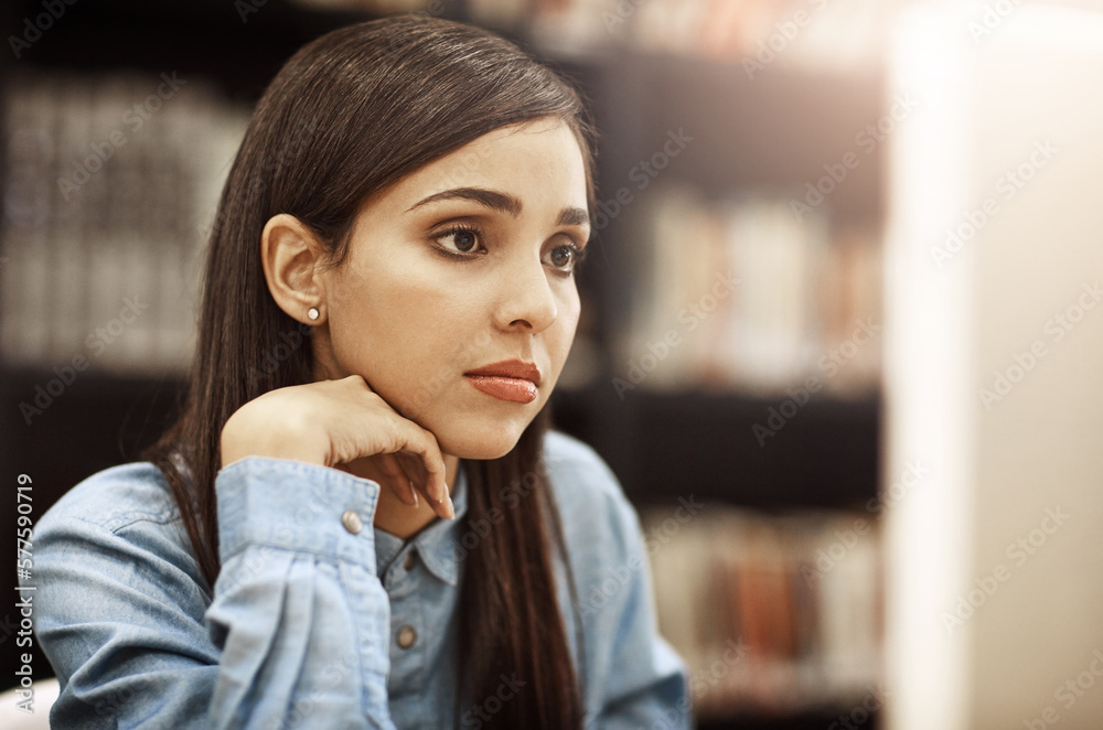 Focused on her bright and successful future. Shot of a university student working on a computer in the library at campus.