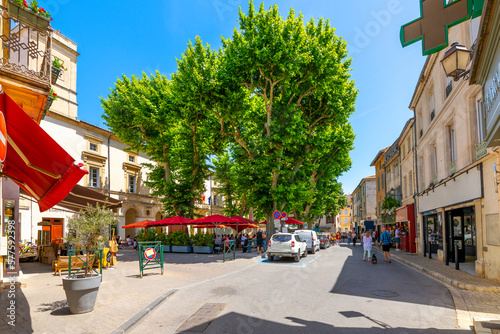 Fototapeta Naklejka Na Ścianę i Meble -  A small town square with shops, trees, and sidewalk cafes in the historic old town of Saint-Remy-de-Provence, France, in the Provence Cote d'Azur region of the French Riviera.