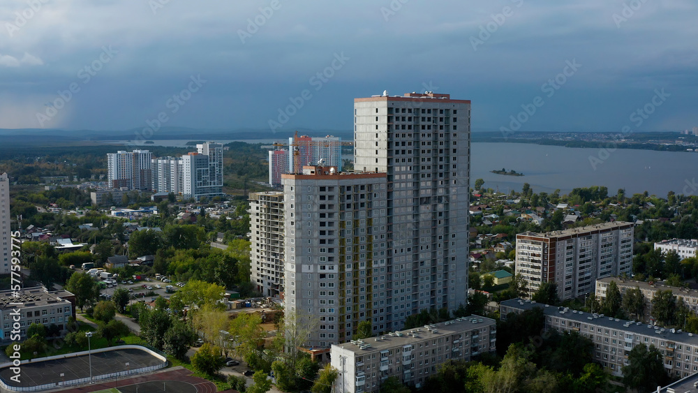 Drone view of tall houses under construction. Stock footage.A built-up city next to a lake against a gray sky.