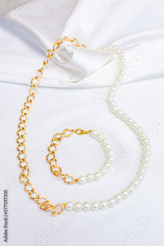 Elegant gold jewelry and mirror on white fabric, closeup