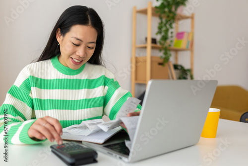 Young adult asian woman calculating home expenses and tax bills at home © Xavier Lorenzo