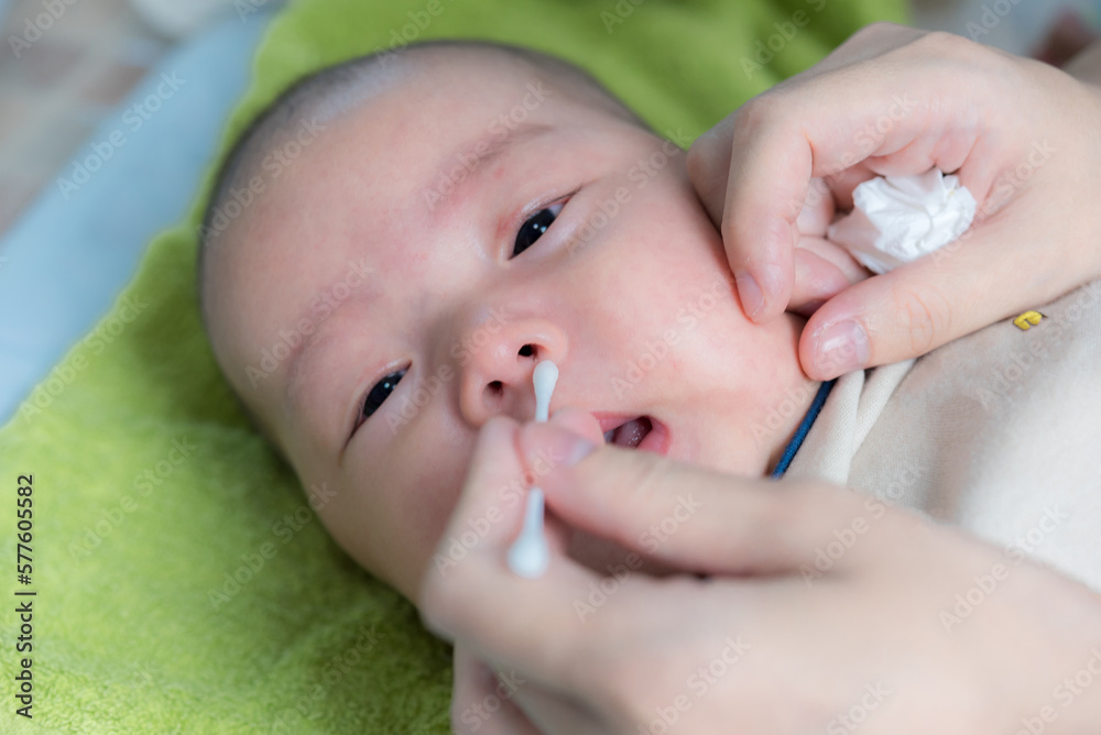 Cleaning Baby Nose With cotton swab, Mother using cotton swap pick up nose a newborn baby Cleaning Baby Nose With cotton swab, Mother using cotton swap pick up nose a newborn baby