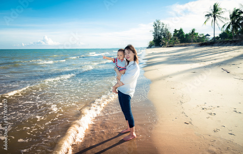 Asian mom and boy play on tropical beach