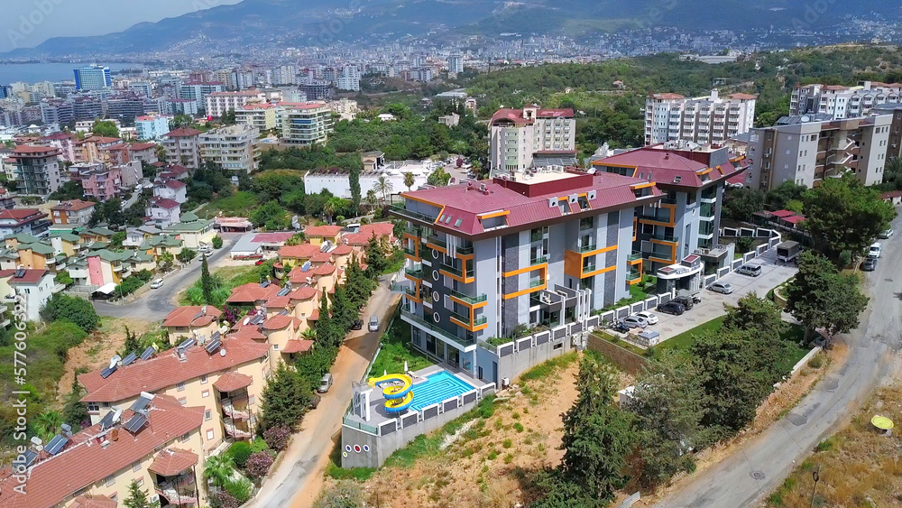Fototapeta premium Picturesque summer city with many houses among greenery. Clip. Buildings and vegetation under the shining sun.