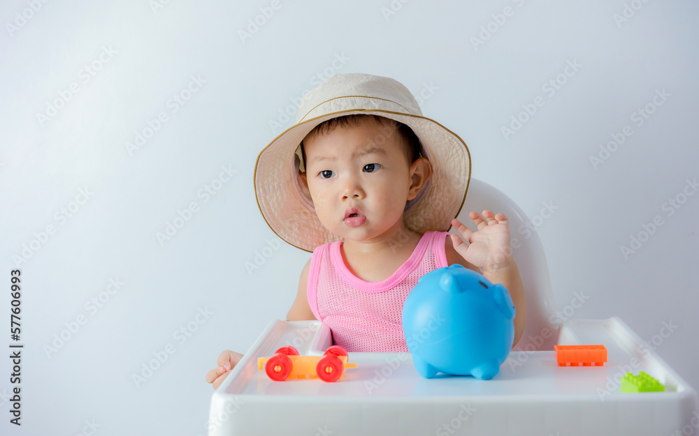 Baby boy inserting a coin into a piggybank on white background - financial concept Baby boy inserting a coin into a piggybank on white background - financial concept
