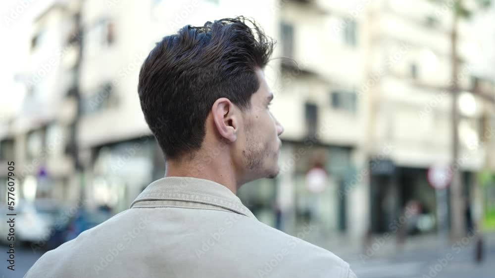 Young hispanic man standing on back view at street