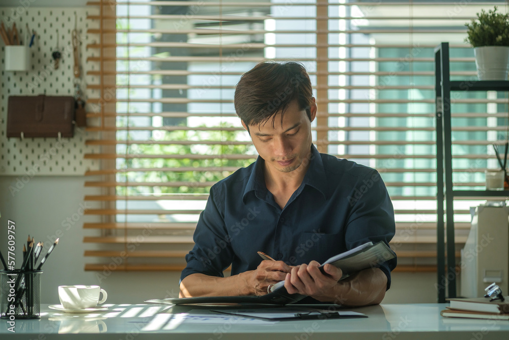 Millennial businessman checking his working schedule plan while sitting on modern workplace. Millennial businessman checking his working schedule plan while sitting on modern workplace.