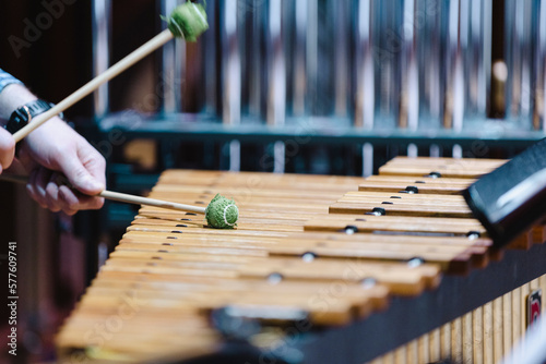 A musician with green mallets playing the marimba during a casual orchestra rehearsal