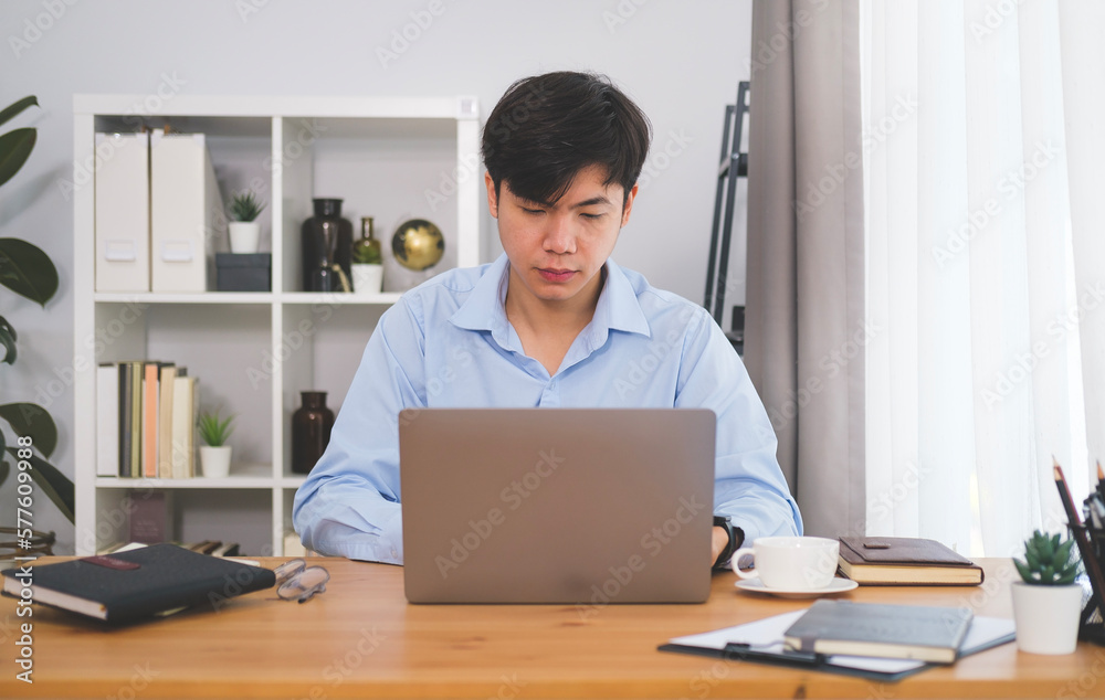 Asian man freelancer working online with computer tablet at home.